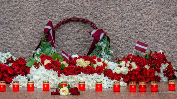 Latvia 100 years. Red and white flowers compositions at the Freedom Monument in city Riga, Latvia