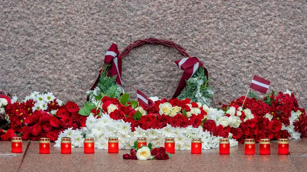 ラトビア 100 赤と白の花の組成物中で都市リガ ラトビアの自由の記念碑 — ストック写真