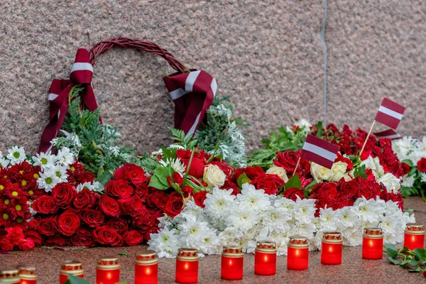Latvia 100 years. Red and white flowers compositions at the Freedom Monument in city Riga, Latvia