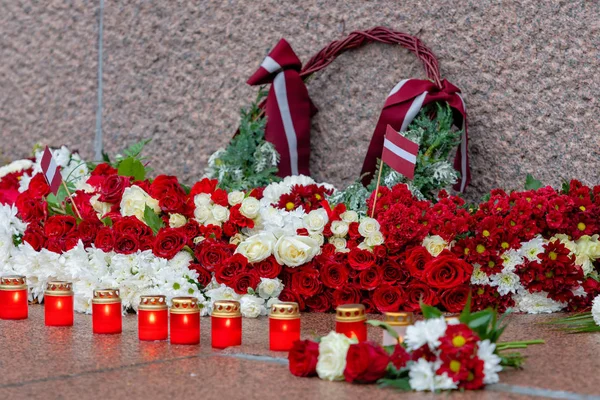 ラトビア 100 赤と白の花の組成物中で都市リガ ラトビアの自由の記念碑 — ストック写真