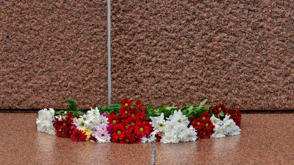 Latvia 100 years. Red and white flowers compositions at the Freedom Monument in city Riga, Latvia
