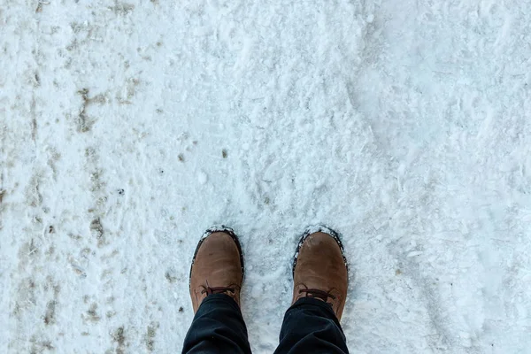 Mans feet in winter boots on the fresh snow.