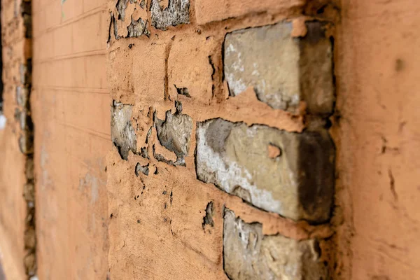 An old brick wall with broken paint. Selective focus close-up photo.