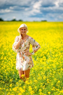 Yumuşak, seçici odak. Sarı çiçek çayır güzel, çekici, sarışın kadın.