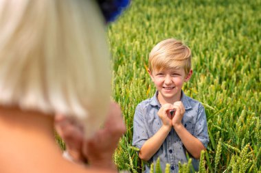 Kalp, annesine gösterilen elleriyle küçük, gülümseyen bir çocuk.