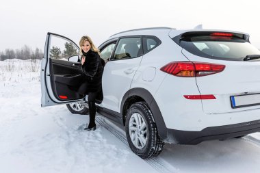 Sarışın kadın beyaz suv arabadan dışarı alır ve geri görünüyor.