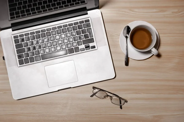 Desk with laptop, eyeglasses and a cup of tea on a wooden table. Top view with copy space. Flat lay - image