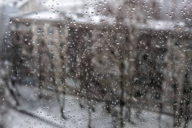 Bir pencereden kar yağışı, kenti su damlaları ile kaplı.