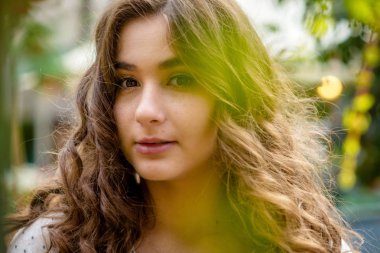 Genç, güzel, esmer kadın portre bahar şehir parkında.