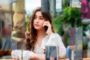 Bir akıllı telefon kullanan bir genç, sempatik, esmer kadın. Bir ayna yüklemesi aracılığıyla bir kadın portresi.