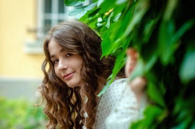 Evin yanında bir parkta genç, sempatik, esmer bir kadın portresi.