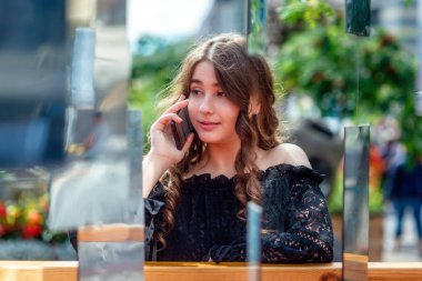 Bir akıllı telefon kullanan bir genç, sempatik, esmer kadın. Bir ayna yüklemesi aracılığıyla bir kadın portresi.