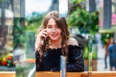 Bir akıllı telefon kullanan bir genç, sempatik, esmer kadın. Bir ayna yüklemesi aracılığıyla bir kadın portresi.