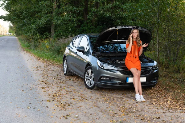 Junge Frau in der Nähe von kaputtem Auto telefoniert und braucht Hilfe — Stockfoto