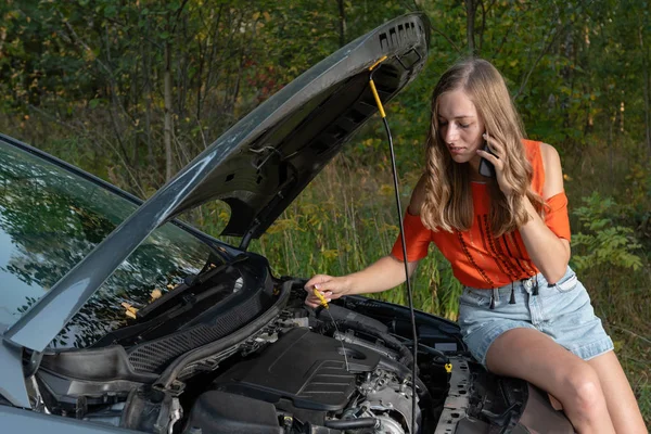 Junge Frau in der Nähe von kaputtem Auto telefoniert und braucht Hilfe — Stockfoto