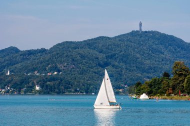 Worthersee, Avusturya - 08 Ağustos 2018: Mesafe dağlarda yaz gölde su turkuaz Worthersee manzaraya. Yaz tatillerini zevk turist.