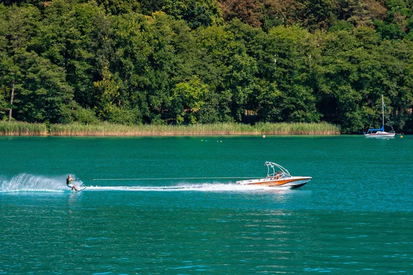 WORTHERSEE, AUTRICHE - 08 AOÛT 2018 : Vue du bateau jusqu'au lac et au littoral. Les résidents locaux et les touristes nagent, conduits par des bateaux à moteur et utilisent d'autres formes de loisirs aquatiques . — Photo