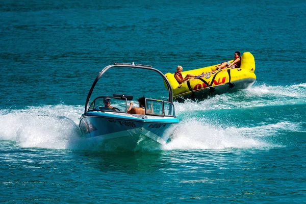 Worthersee, Avusturya - 08 Ağustos 2018: Mutlu gençler, şişme konumlar, sürücünün arkasındaki gölde bir motorlu tekne.
