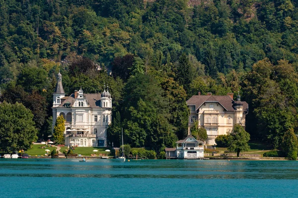 WORTHERSEE, AUSTRIA - 08 AGOSTO 2018: Grandes paisajes desde el barco hasta la orilla del lago, hermosos edificios, montañas, bosques, carreteras . — Foto de Stock