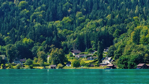 WORTHERSEE, AUSTRIA - 08 AGOSTO 2018: Grandes paisajes desde el barco hasta la orilla del lago, hermosos edificios, montañas, bosques, carreteras . — Foto de Stock