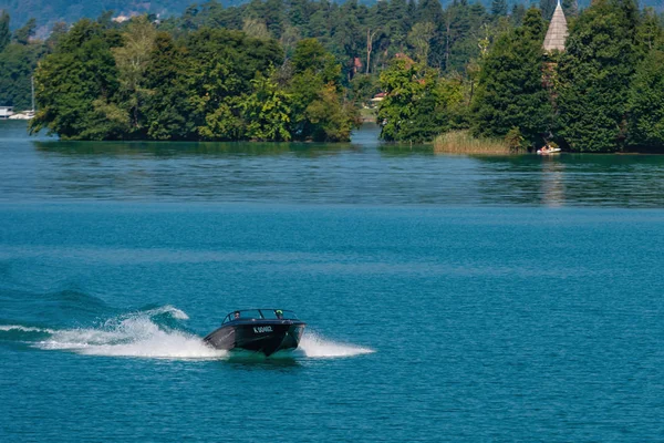 WORTHERSEE, AUSTRIA - สิงหาคม 08, 2018: มุมมองจากเรือไปยังทะเลสาบและชายฝั่ง ผู้อยู่อาศัยในท้องถิ่นและนักท่องเที่ยวว่ายน้ําขับเคลื่อนด้วยเรือยนต์และใช้รูปแบบอื่น ๆ ของการพักผ่อนหย่อนใจทางน้ํา . — ภาพถ่ายสต็อก