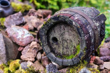 Siyah kil sürahi ve taş yığını üzerinde eski ahşap varil. 