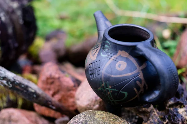 Black clay jug and old wooden barrel on stone pile. — Stock Photo, Image