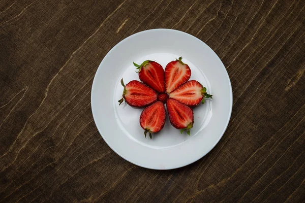 Fresas en un plato blanco sobre una mesa de madera. concepto de fondo creeativo. - Imagen —  Fotos de Stock