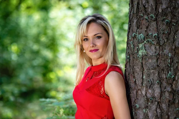 Vacker, blond kvinna stående på en skog-bakgrund. — Stockfoto