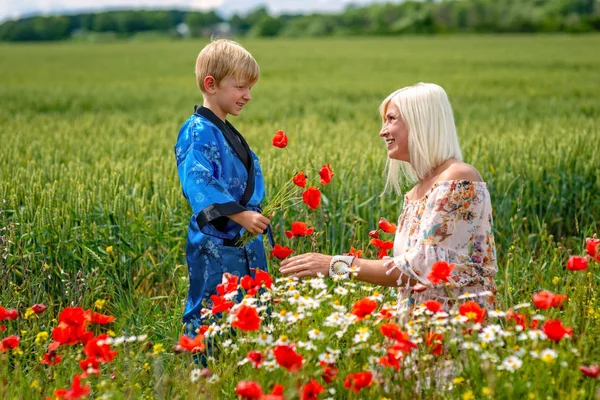 Mamá con su hijo en un prado magnífico. El chico la sorprendió. —  Fotos de Stock