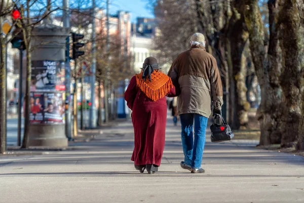 Ett par äldre människor i händerna går genom stadens gata. Bakifrån. — Stockfoto