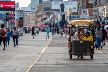 Atlantic City, New Jersey - 18 Haziran 2019: Bir pedicab, müşterilerini restoranlar, mağazalar ve kumarhanelerle dolu Boardwalk'un önünden geçirmeye zorluyor.