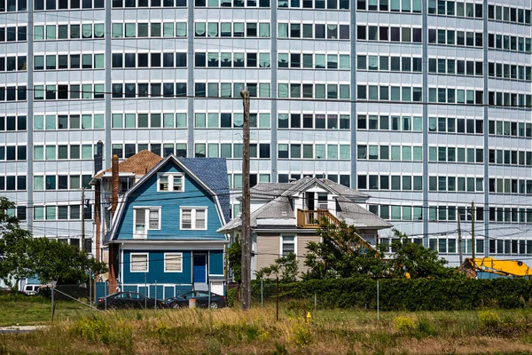 An ancient wooden building to a modern multi-storey houses in the background. — Stock Photo, Image