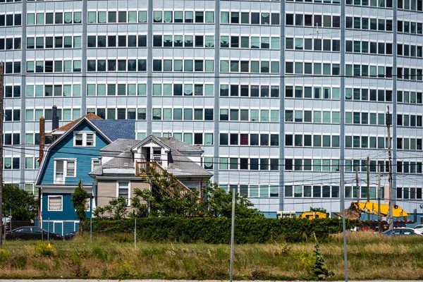 Un antiguo edificio de madera a unas modernas casas de varios pisos en el fondo . —  Fotos de Stock