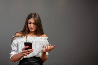 Cep telefonu ile konuşurken gri duvar arka plan üzerinde izole poz heyecanlı bir şok duygusal genç kadın Görüntü.