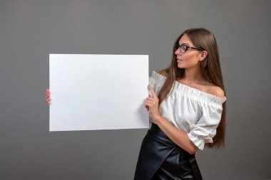 Gri backg izole boş bir billboard tutan güzel kadın