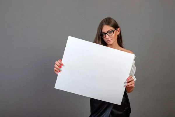 Beautiful woman holding a blank billboard isolated on gray backg — Stock Photo, Image