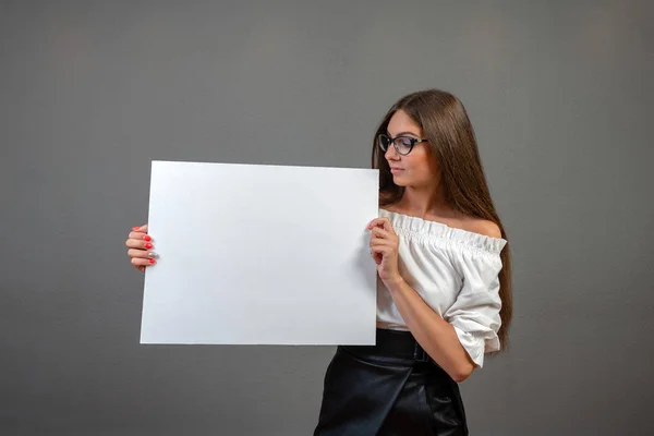 Beautiful woman holding a blank billboard isolated on gray backg — Stock Photo, Image