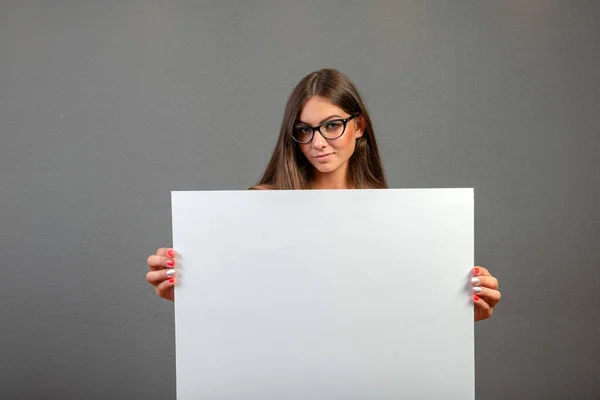 Beautiful woman holding a blank billboard isolated on gray backg — Stock Photo, Image