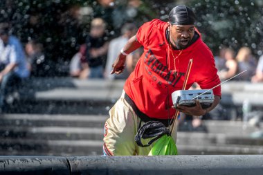 New York, ABD - 21 Haziran 2019: Halka açık bir parktaki çeşmede, kırmızı elbiseli siyah bir adam şarkı lar seslendirdi.