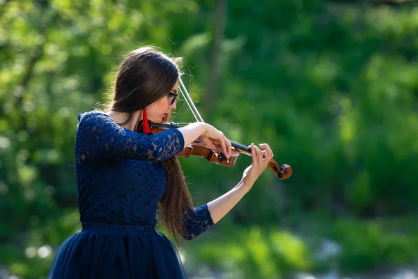 Una joven tocando el violín en el parque. Profundidad superficial del campo — Foto de Stock