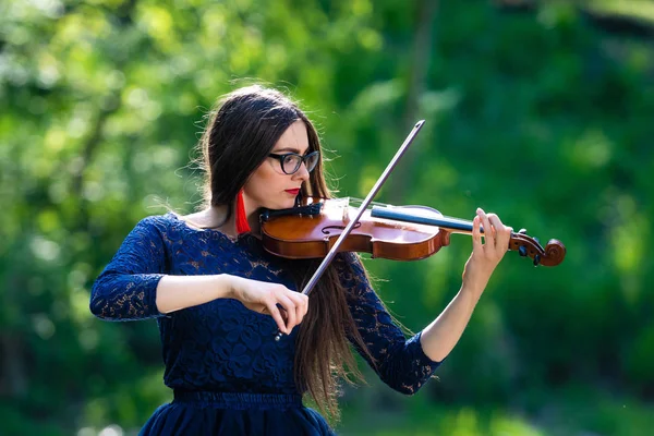 Una joven tocando el violín en el parque. Profundidad superficial del campo — Foto de Stock