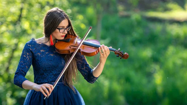 Una joven tocando el violín en el parque. Profundidad superficial del campo — Foto de Stock