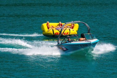 Worthersee, Avusturya - 08 Ağustos 2018: Mutlu gençler, şişme konumlar, sürücünün arkasındaki gölde bir motorlu tekne.