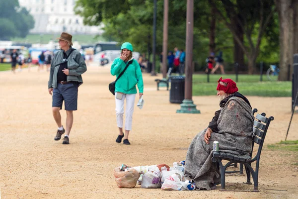 Вашингтон, ОКРУГ КОЛУМБИЯ - 9 июня 2019 года. Бездомный сидит на скамейке у пешеходной дорожки . — стоковое фото