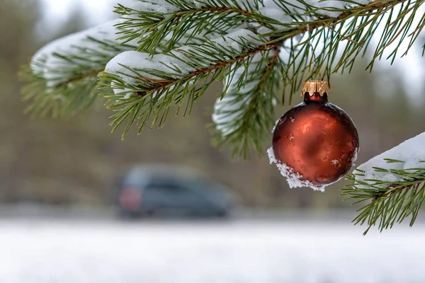 Červené vánoční koule na sněhu zahrnuty jedle větev vedle dálnice. — Stock fotografie