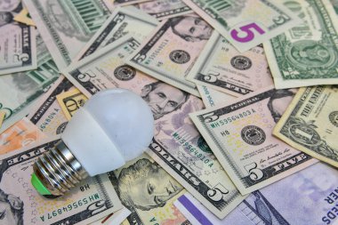 Farklı ülkelerin para birimi notlarının arka planında ampul var. Ekonomi kavramı