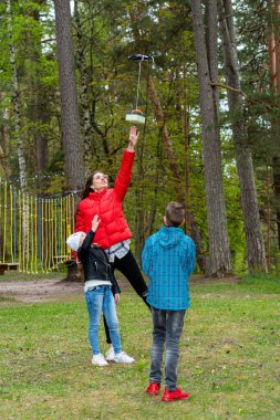 Parkta iki kız kardeş ve bir erkek kardeş sıcak bir bahar gününün tadını çıkarın ve bir dronla eğlenin, yaşam tarzı ve eğlence kavramı.