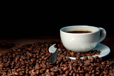 Beyaz kahve fincanı ve koyu ahşap arka planda kahve çekirdekleri - görüntü