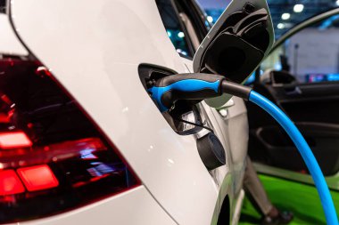 Elektrikli araba şarjı için güç kaynağı. Elektrikli araba şarj istasyonu. Şarj olan bir elektrikli arabaya takılan güç kaynağını kapat - görüntü